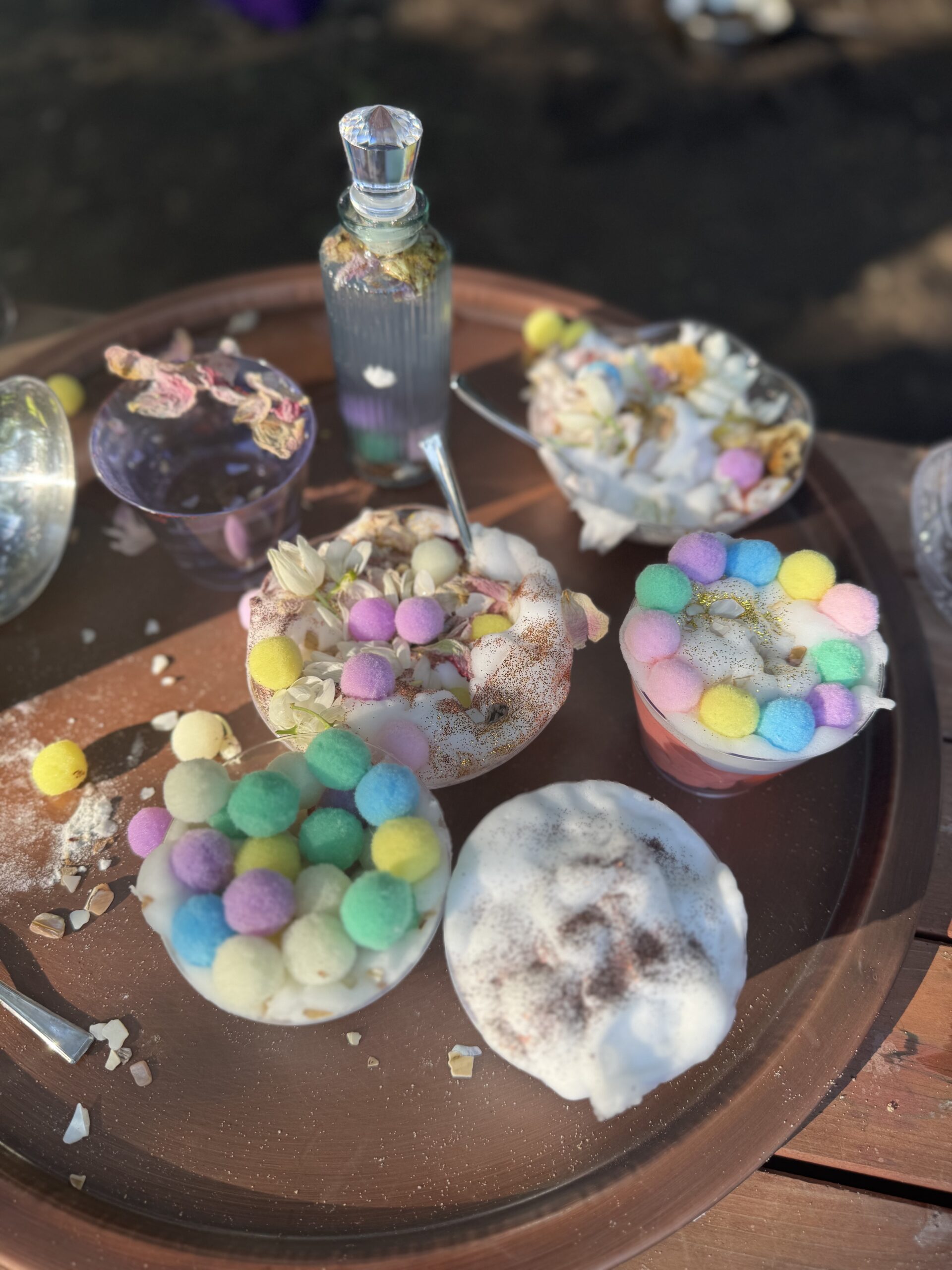 Outdoor table filled with bowls of colorful mud kitchen creations